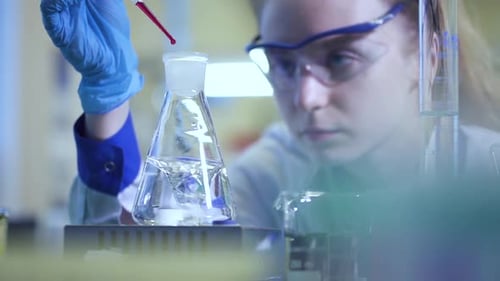 Woman Scientist in the Laboratory Mixing Chemical Reagent Yellow Liquid in Stirring Beaker Spbd