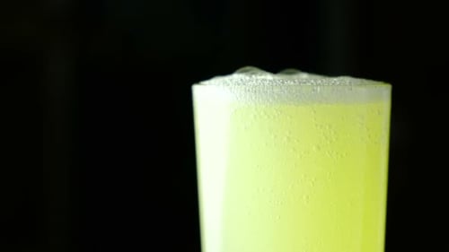 Carbonated Drink Yellow Poured Into a Glass on a Black Background