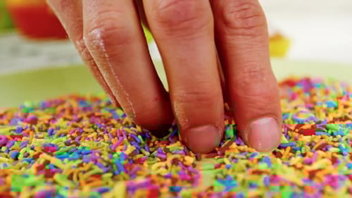 Hand Sprinkling Colorful Candy on Cupcake