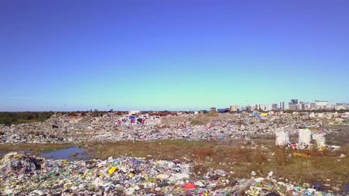 Drone view of city dump on background of sea, the city and the mountains.