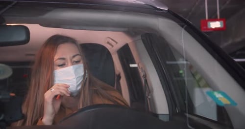 Woman in Car Puts On and Removes Mask