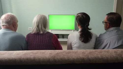 Toute la famille regarde la télévision. Écran vert.
