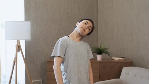 Woman Stretches Neck and Shoulder Muscles Indoors