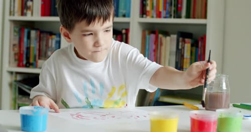 Cute Child Painting with Paint Brush at Table