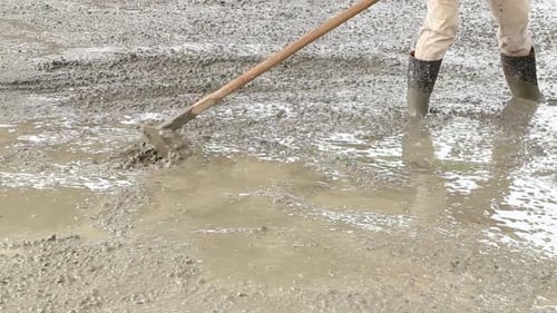 Men Leveling Wet Cement at Construction Site