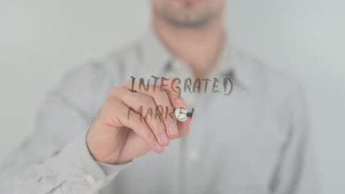 Man Writes Integrated Marketing On Transparent Board