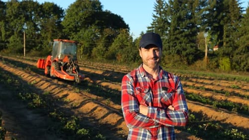 Smiling Farmer Standing in Field with Tractor