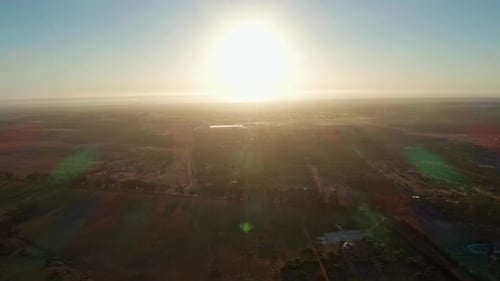 Sun Setting Over the Plain with Sun Rays Reflecting on the Camera