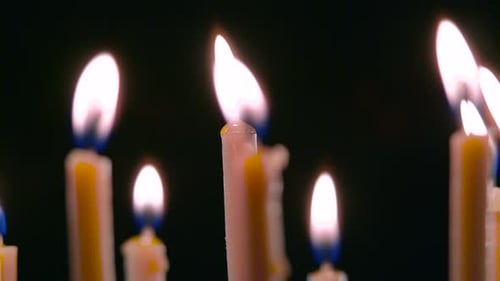Les bougies brûlent, une belle flamme orange, puis sortent du vent, fond noir, gros plan