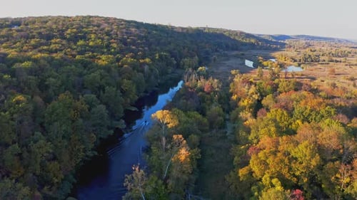 Motorboat Sails on Narrow River Between Lush Trees in Autumn
