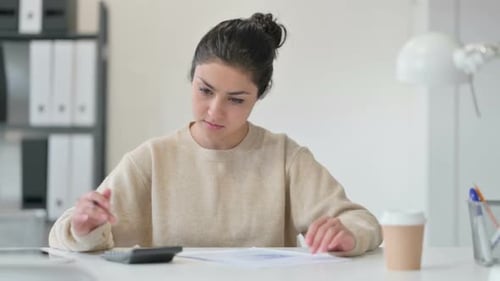 Young Woman Calculates Business Numbers at Desk