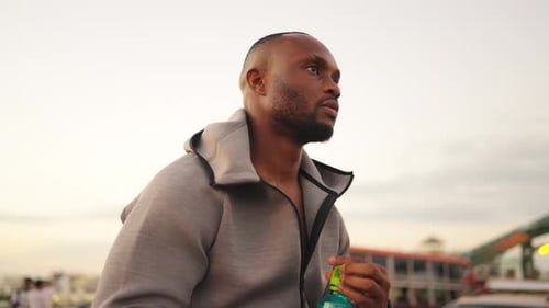 4K Handsome African man in sportswear drinking water from a bottle while jogging in the city