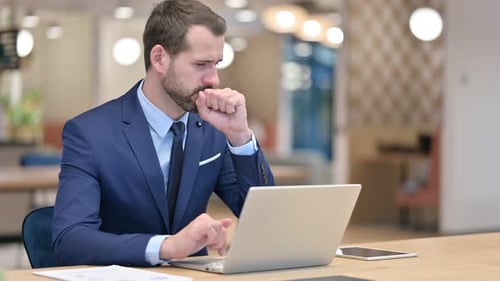 Sick Businessman with Laptop Coughing in Office
