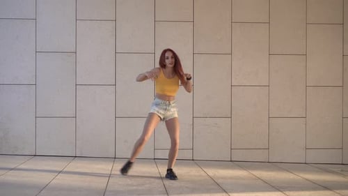 Energetic Redhead Woman Dancing in an Urban Setting