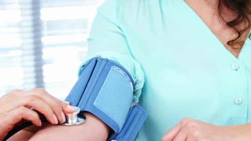Doctor Using Stethoscope to Check Patient Blood Pressure