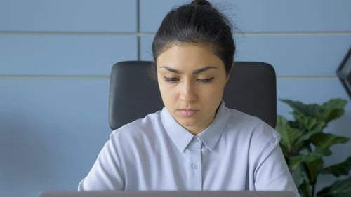 Close-Up Portrait Of A Young Indian Woman Looking Thoughtfully At A Monitor Screen