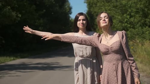 Two Women Hitchhiking on Country Road