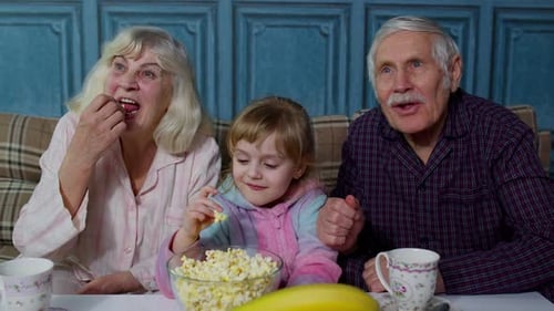 Grandparents and Child Enjoying Movie Night with Popcorn