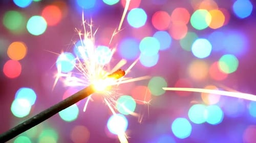 Sparkler Burns Against Bokeh Christmas Lights Background