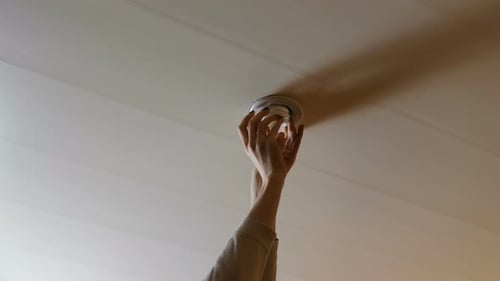 Hands Changing a Lightbulb on Ceiling