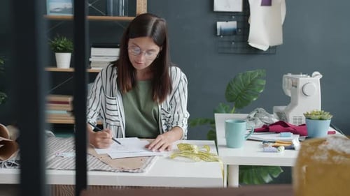 Slow Motion of Young Woman Sketching Stylish Clothes Working in Fashion Studio Alone