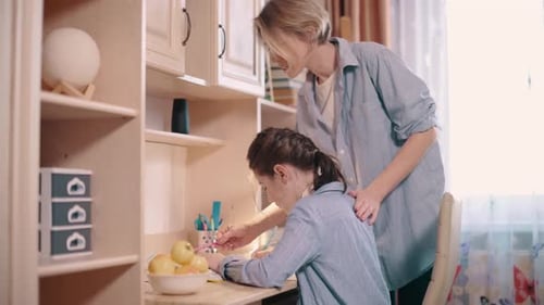 Woman Helping Girl with Homework at Desk