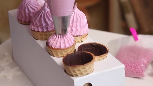 Eine Frau macht Marshmallows in Waffeltüten. Mit einem Gebäckbeutel.