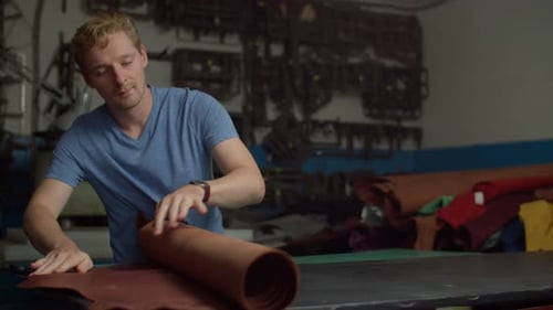 Leather Worker Unrolling Brown Leather in Workshop