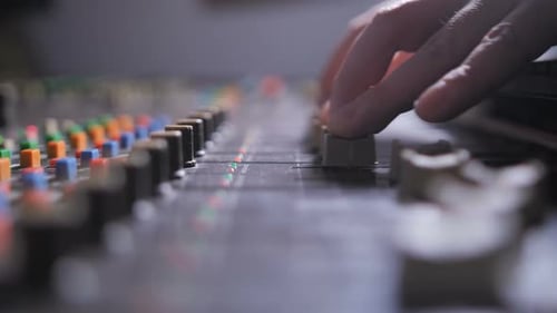 Sound Engineer Adjusts Mixing Board Controls
