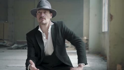 Porträt Selbstbewusster Mann sitzt auf dem Stuhl in der zerstörten Garage mit einem Fedorahut und einem Klassisch