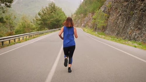 Woman Running on Road in Mountain Landscape