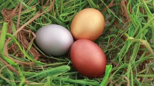 Tres huevos de Pascua dorados sobre hierba