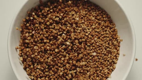 Raw Buckwheat Grains Poured into White Bowl