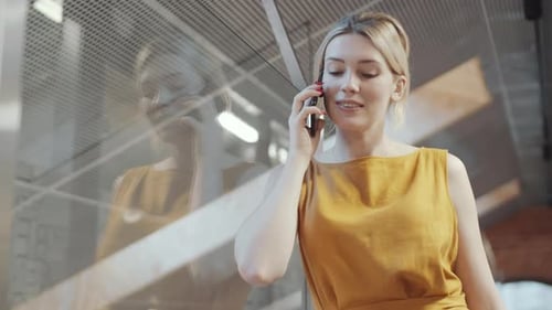 Pretty Blonde Businesswoman Talking on Cell Phone in Modern Office