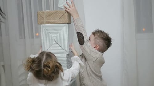 Boy and Girl Stacking Christmas Gifts