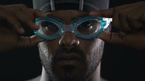 Man Wearing Swim Cap Puts on Goggles