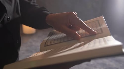 Hand umblätternde Koran-Seite.