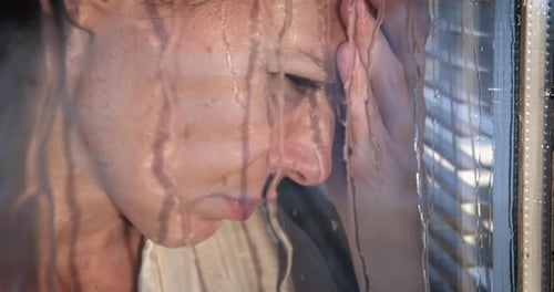 Sad Woman Holding Face near Window on Rainy Day