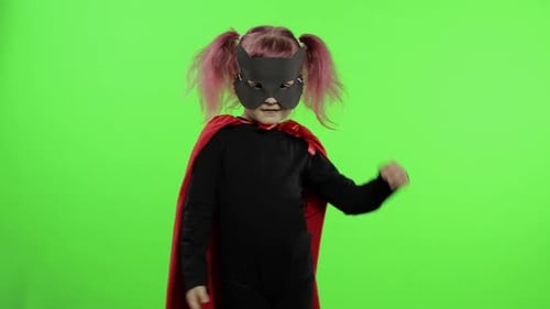 Une fillette drôle en costume et masque joue un super héros. Journée nationale des super-héros