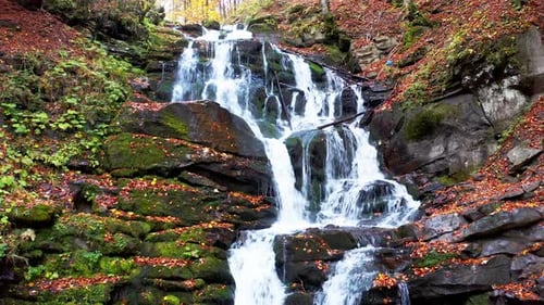 Narrow Stream Falling Down Mountain Slope in Autumn Forest