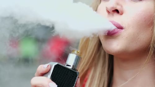 Chica joven con estilo en una ciudad con vape
