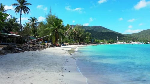 Paradise beach with white sand washed by calm clear water of turquoise lagoon and palm trees on shor