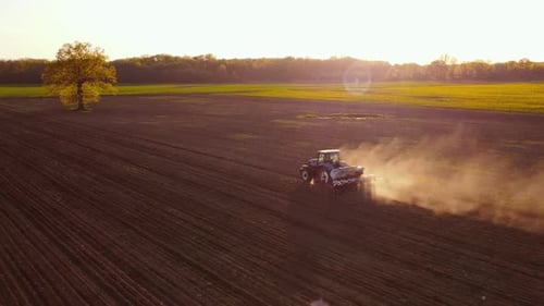 Tractor Working in Field at Sunset