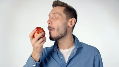 Young Man Eating an Apple in Studio