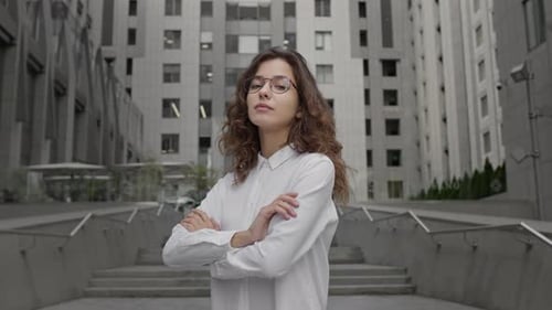 Young Girl Dressed In Business Style Clothes Stands On The Background Of Tall Building