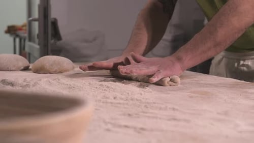 Baker Shaping Dough on Floured Surface in Kitchen