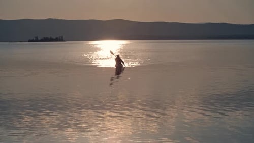 Kayaker Paddles on Lake at Sunset