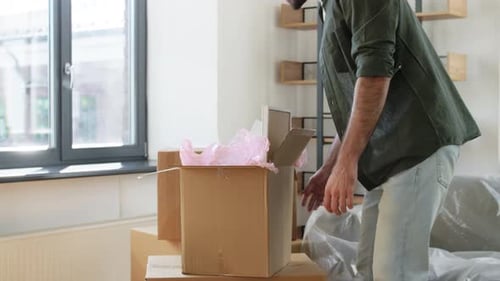 Smiling Man Moving into New Home with Boxes