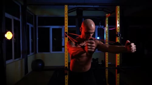 Frontansicht der muskulösen, hemdlosen Bodybuilder-Trainingstruhe im Fitnessstudio in dunkler Atmosphäre