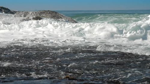 Foaming Ocean Waves Roll on Brown Rock Near Coastline